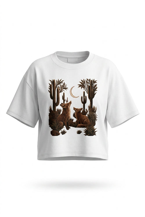 A white short-sleeve crop top t-shirt featuring a graphic print of two brown foxes sitting among cacti under a crescent moon.
