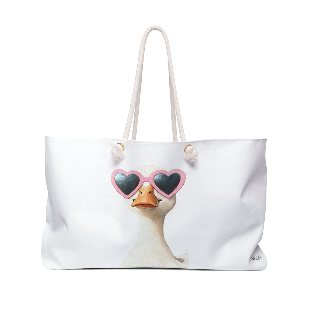 A white canvas tote bag with cream-colored rope handles, featuring a printed graphic of a duck wearing pink heart-shaped sunglasses on the front.