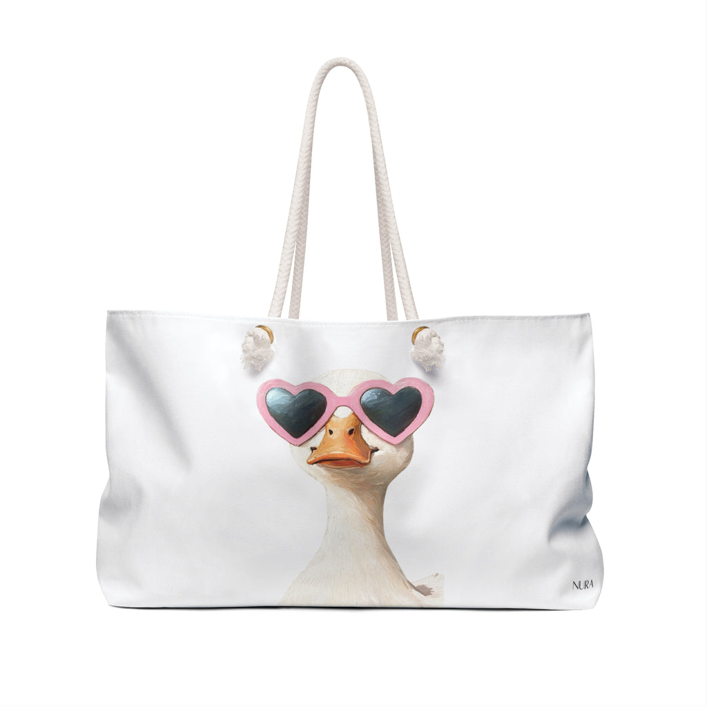 A white canvas tote bag with cream rope handles, featuring a printed illustration of a duck wearing pink heart-shaped sunglasses on the front.