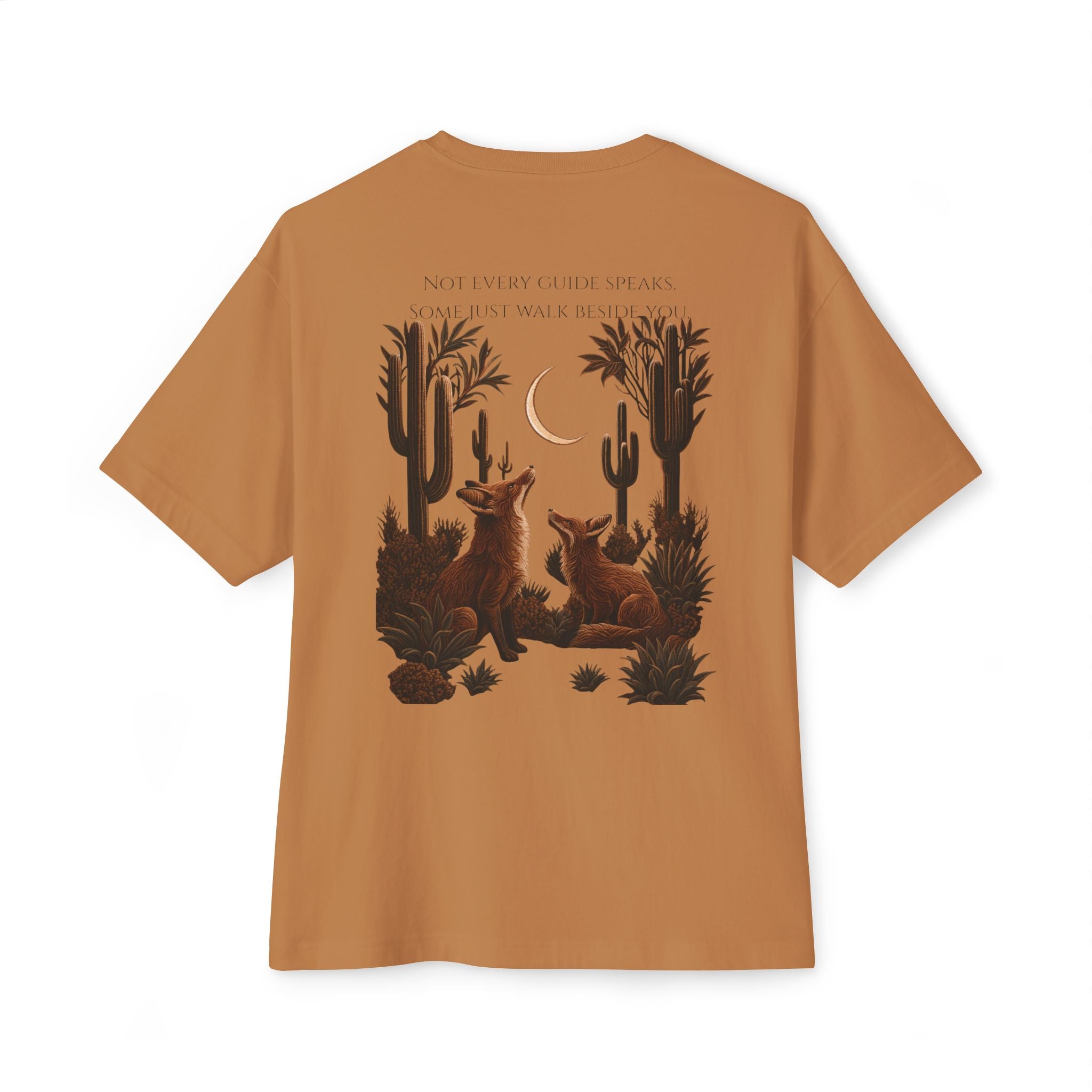 A tan short-sleeve t-shirt shown from the back, featuring a detailed desert graphic of two foxes under a crescent moon with cacti and the text 'NOT EVERY GUIDE SPEAKS. SOME JUST WALK IN SHADOW.
