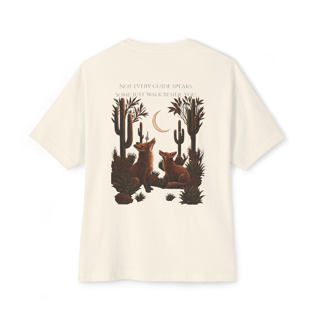 An off-white short-sleeve t-shirt with a large graphic print on the back featuring two brown foxes in a desert landscape with cacti, a crescent moon, and the text 'NOT EVERY GUIDE SPEAKS. SOME JUST WALK BEHIND YOU.