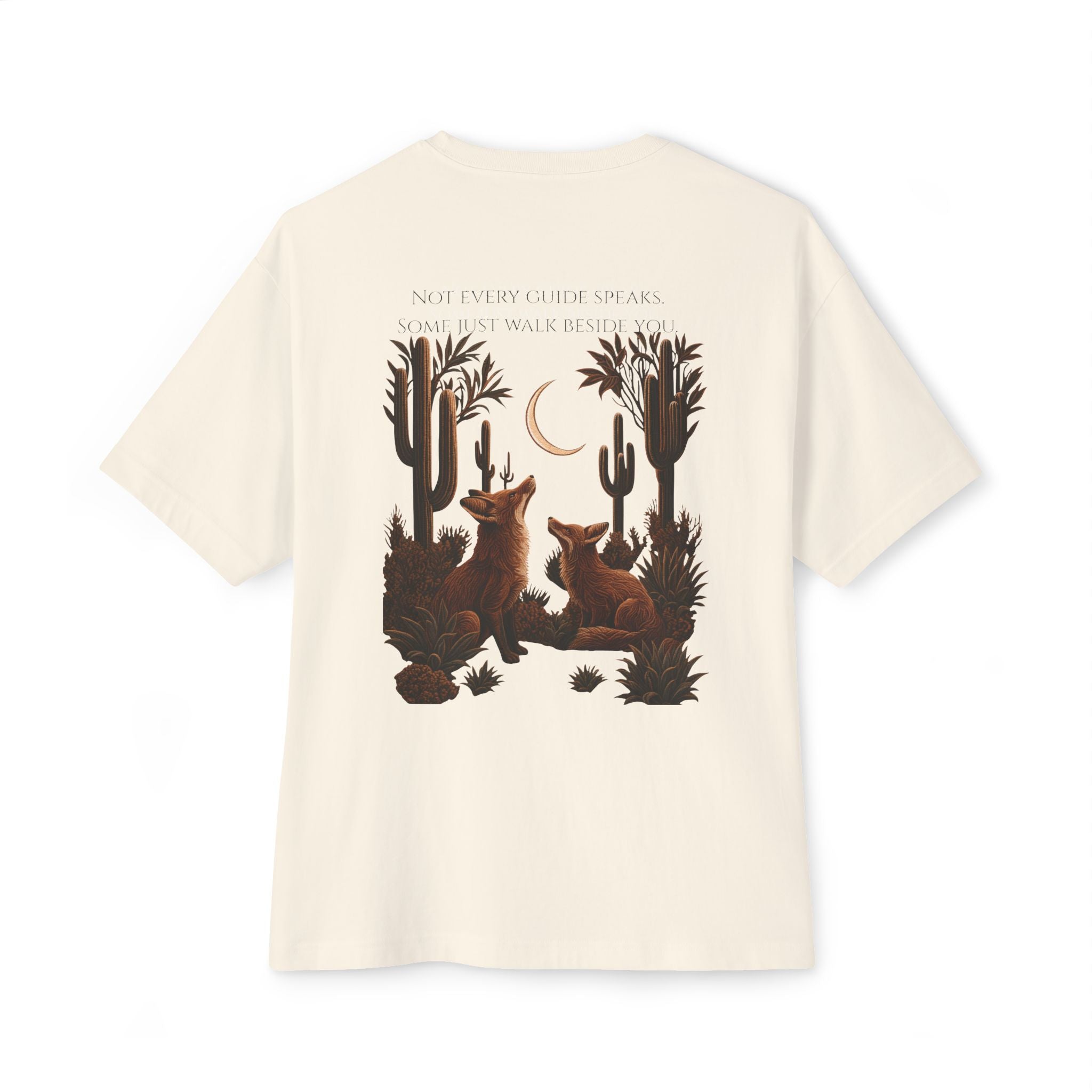 An off-white short-sleeve t-shirt with a large graphic print on the back featuring two brown foxes in a desert landscape with cacti, a crescent moon, and the text 'NOT EVERY GUIDE SPEAKS. SOME JUST WALK BEHIND YOU.